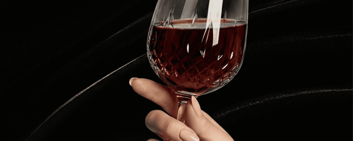A hand with manicured nails holding a wine glass, symbolizing stylish elegance.